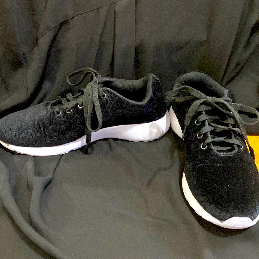 These are black sneakers with a rose design in the cloth on the outside.